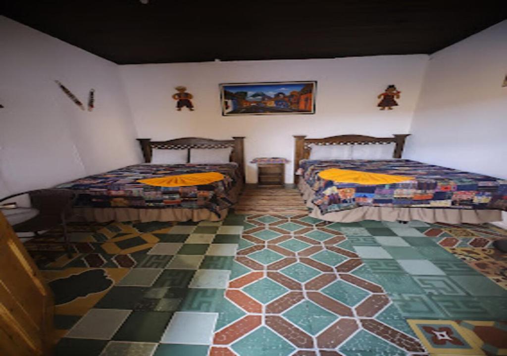 a room with two beds and a rug at Hotel Francisco's la Merced in Antigua Guatemala