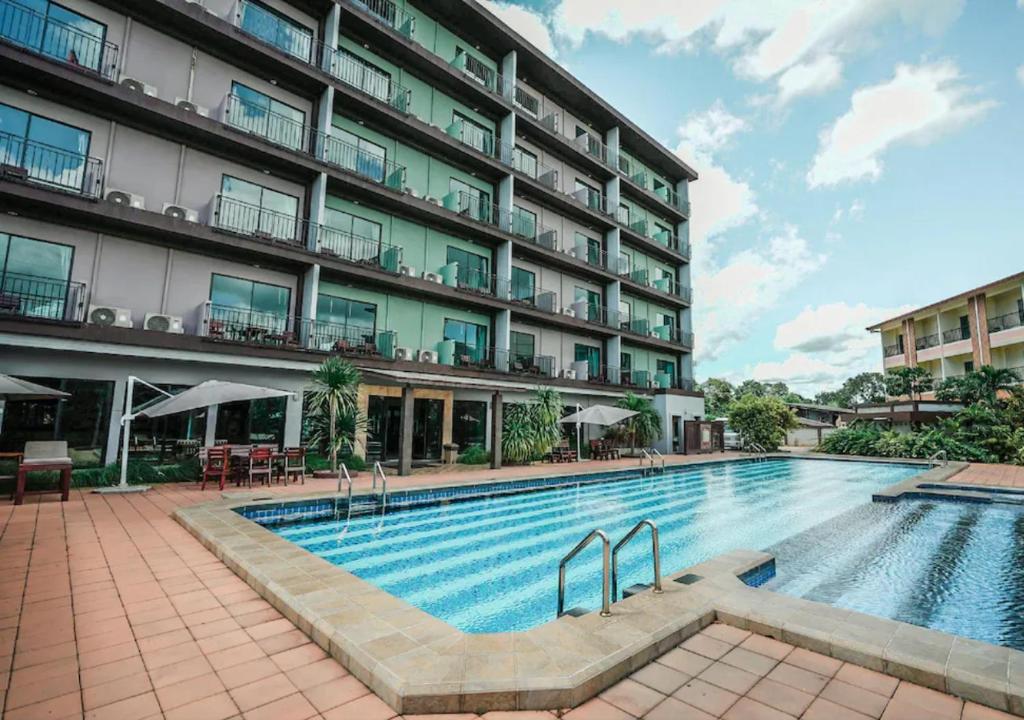 a swimming pool in front of a building at Savotel Hotel in Na Jomtien