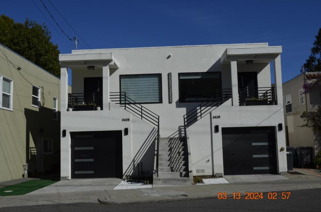 a white house with two garage doors at Dimond Abode Vacation Home 2 in Oakland