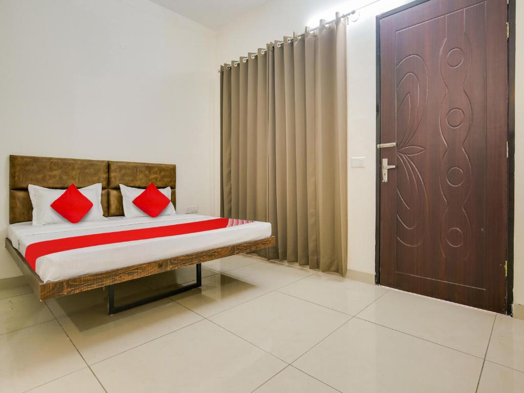 a bedroom with a bed with red pillows and a door at Super OYO Hotel Comfort Regency in Ludhiana