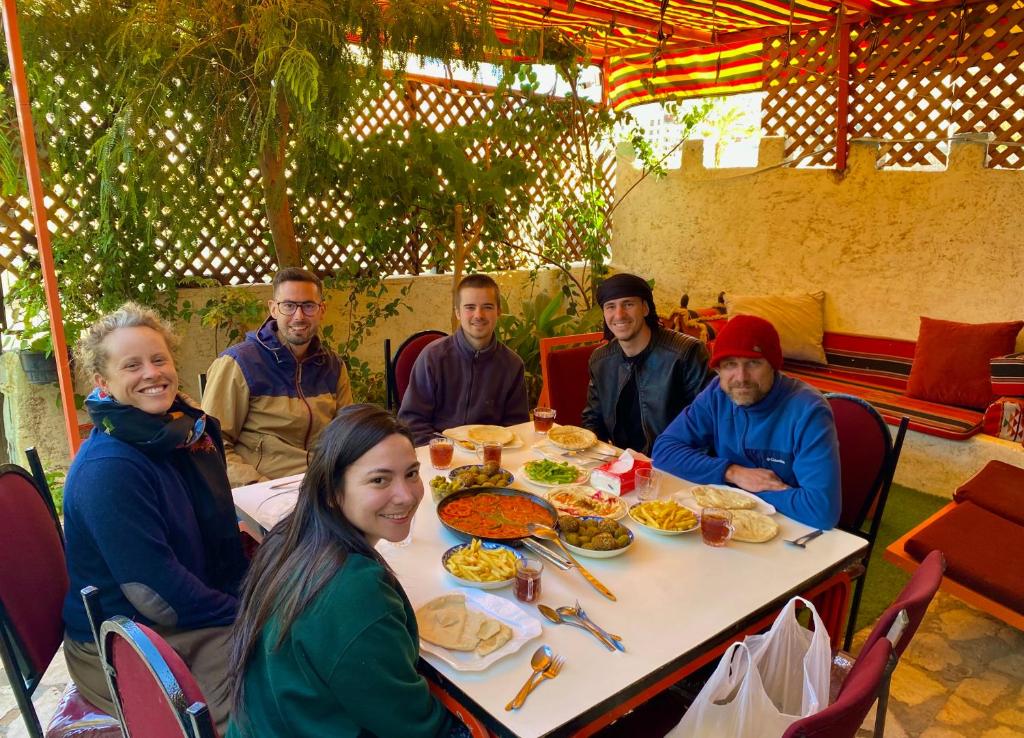 un grupo de personas sentadas alrededor de una mesa comiendo comida en Al-Amer Hostel 1, en Áqaba