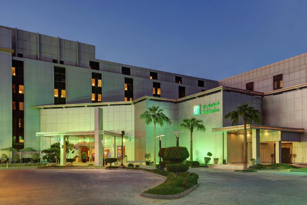 a large building with palm trees in front of it at Holiday Inn Riyadh Al Qasr, an IHG Hotel in Riyadh