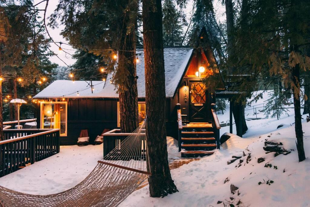 Cabaña de madera en la nieve con hamaca en la parte delantera en Mid-Century Cabin Perfect for Romantic Getaway, en Running Springs
