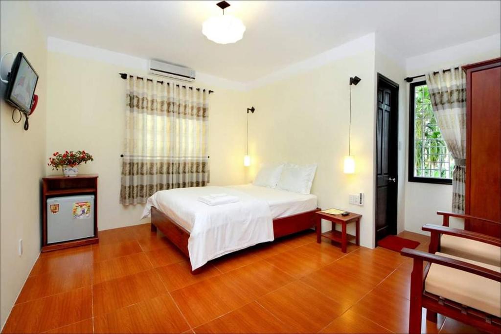 a bedroom with a white bed and a wooden floor at Hợp ý MAVINA cơ sở II in Hoi An
