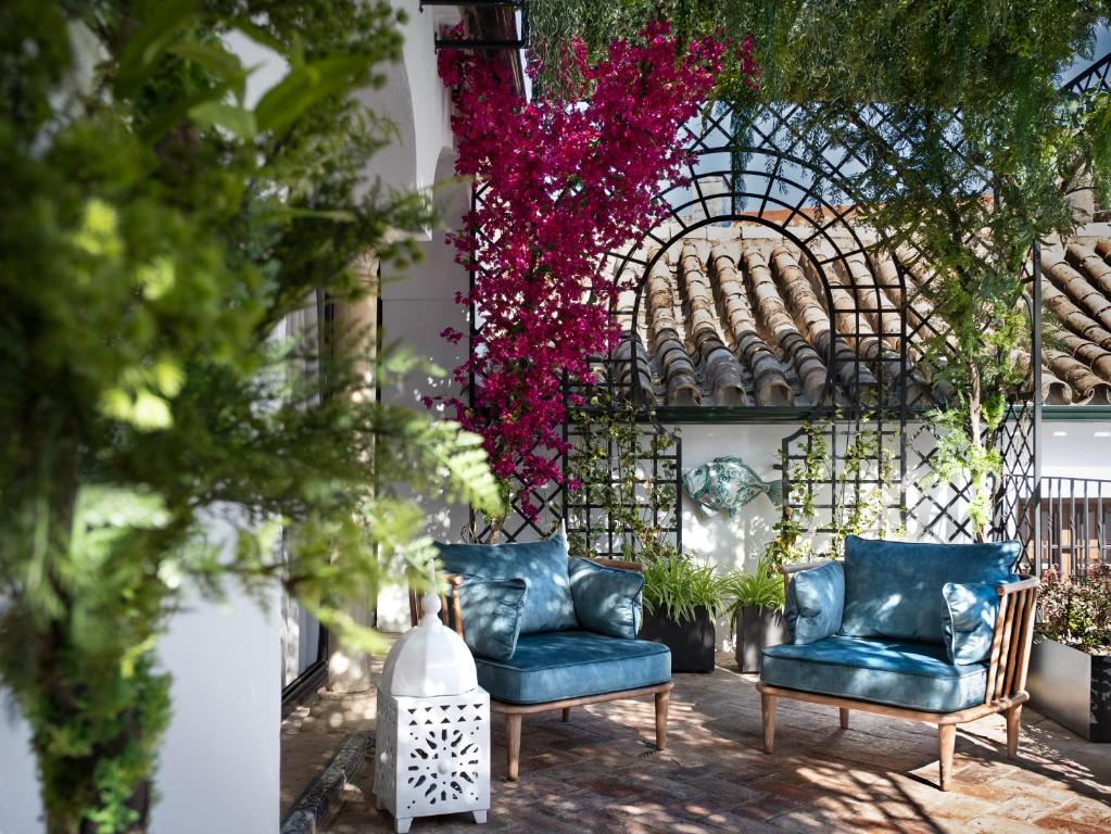 two blue chairs sitting in a courtyard with flowers at Gandesa, Palace House in Seville
