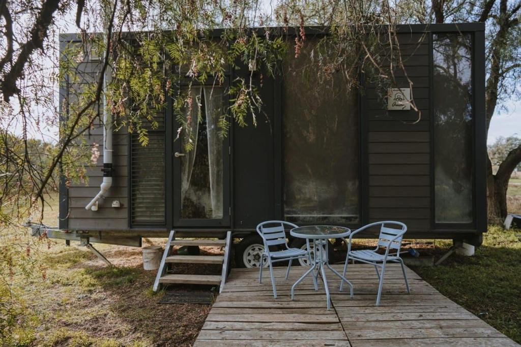 a tiny house with a table and chairs on a deck at Organic Farm Stay in Numurkah