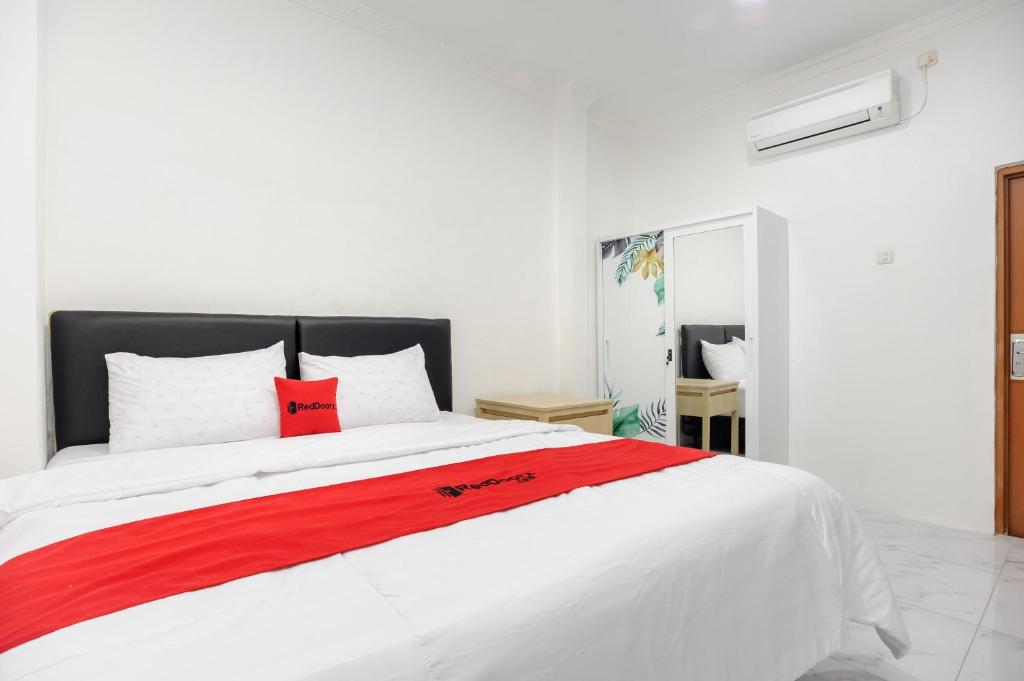 ein großes weißes Bett mit einer roten Decke drauf in der Unterkunft RedDoorz Syariah @ Sakura Hotel Jatiwaringin in Bekasi