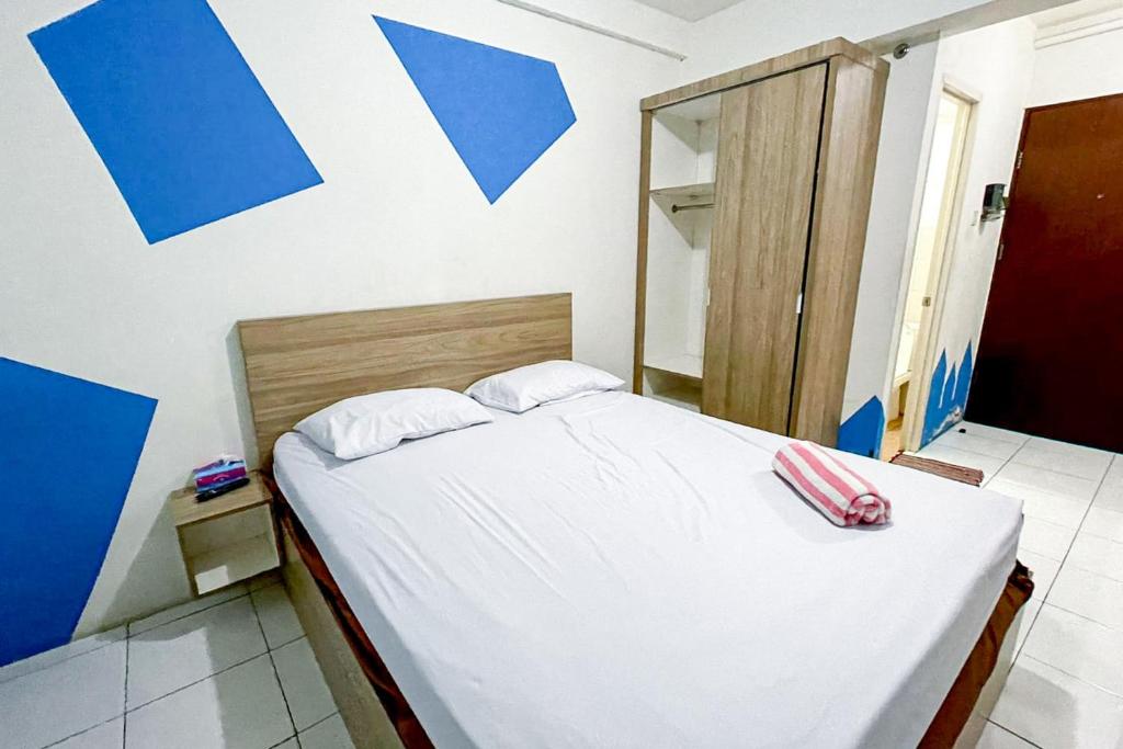 a bedroom with a bed with white sheets and a mirror at Apartemen Riverview Cikarang by Room PDL 99 in Bekasi