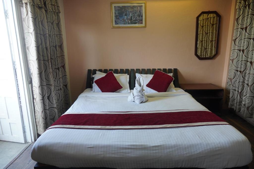 1 dormitorio con 1 cama grande con almohadas rojas y blancas en Hotel Travelers Home, en Katmandú