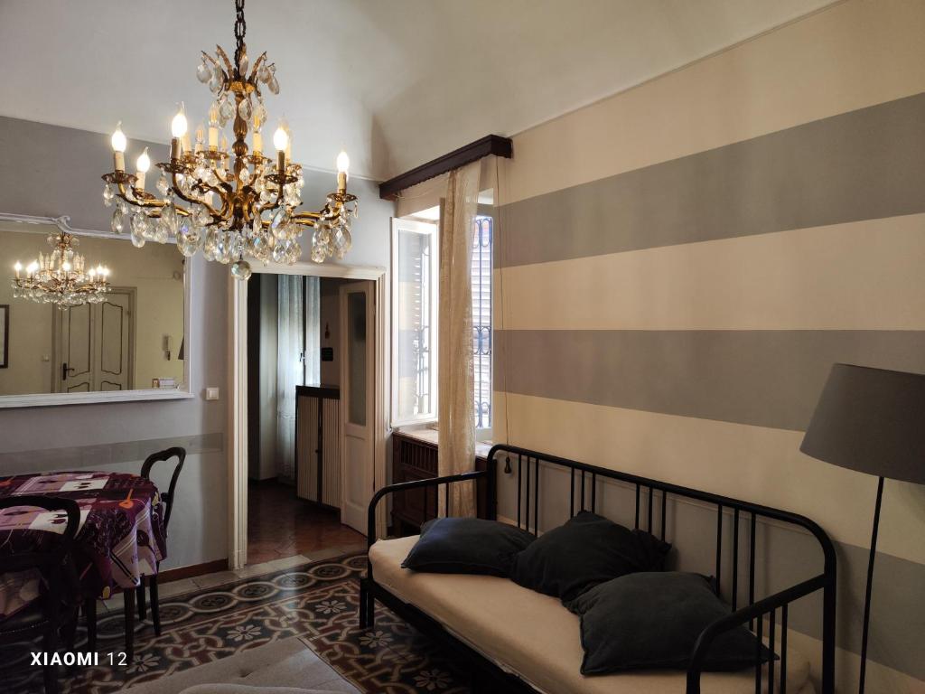 een woonkamer met een bed en een kroonluchter bij Sotto la Torre - Under the Tower in Novi Ligure