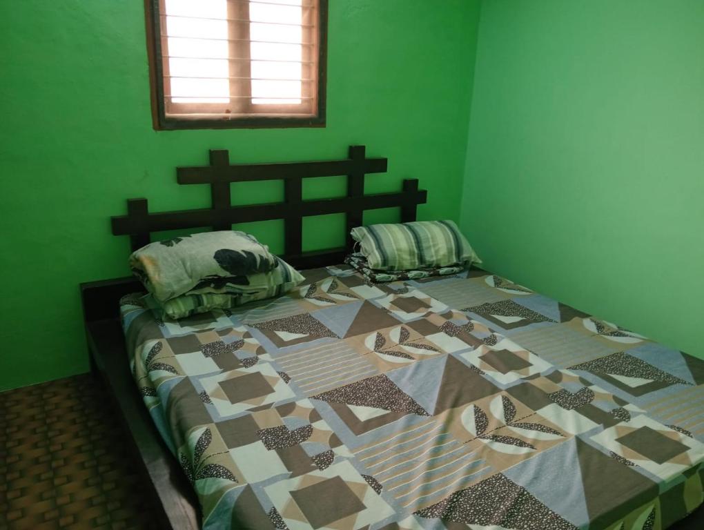 a green bedroom with a bed with a quilt on it at KKA RESIDENCY in Coimbatore