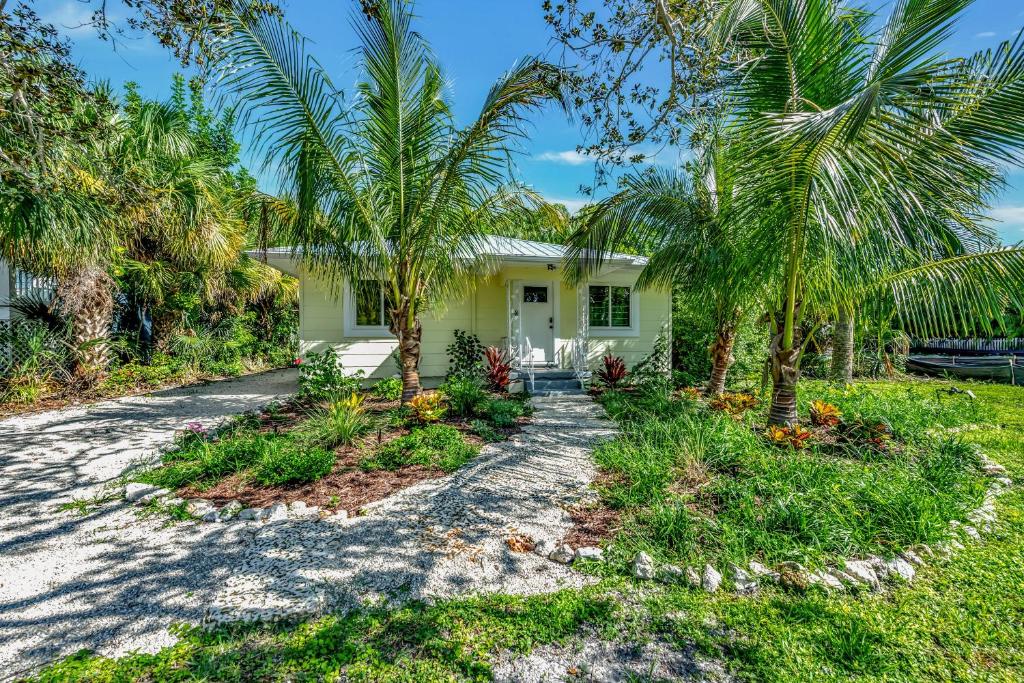 a house with palm trees in front of it at Casa Posada - So Close You Can Hear the Waves Historic Beach Cottage w Beach Gear in Anna Maria