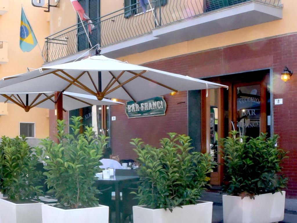 a table with an umbrella in front of a restaurant at Albergo La Perla in Orbetello