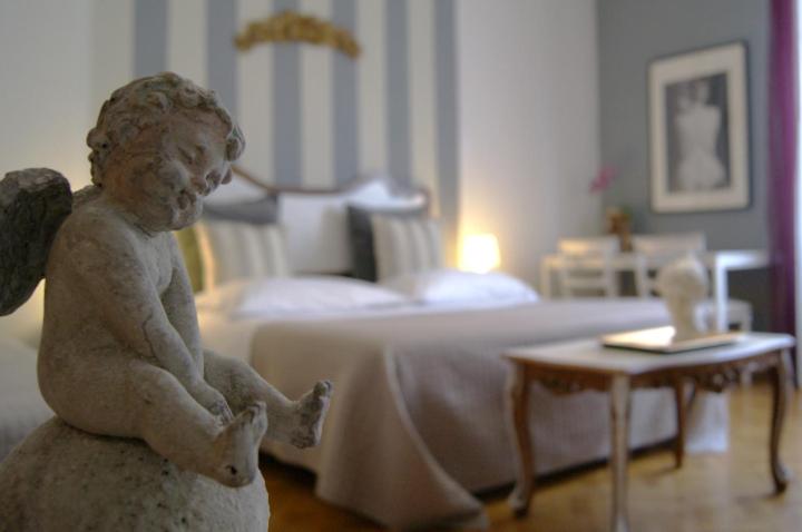 una estatua de una niña sentada frente a una cama en Ay Home B&B, en Bolonia