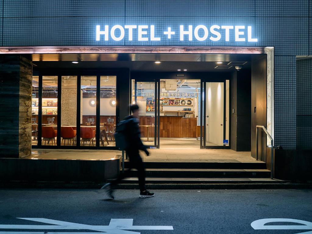 a person walking in front of a hotel hostel at Hotel Plus Hostel TOKYO KAWASAKI in Kawasaki