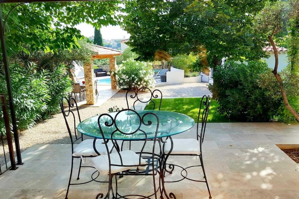 a glass table and chairs on a patio at Une villa en Provence, piscine et jardin ombragé in Velaux