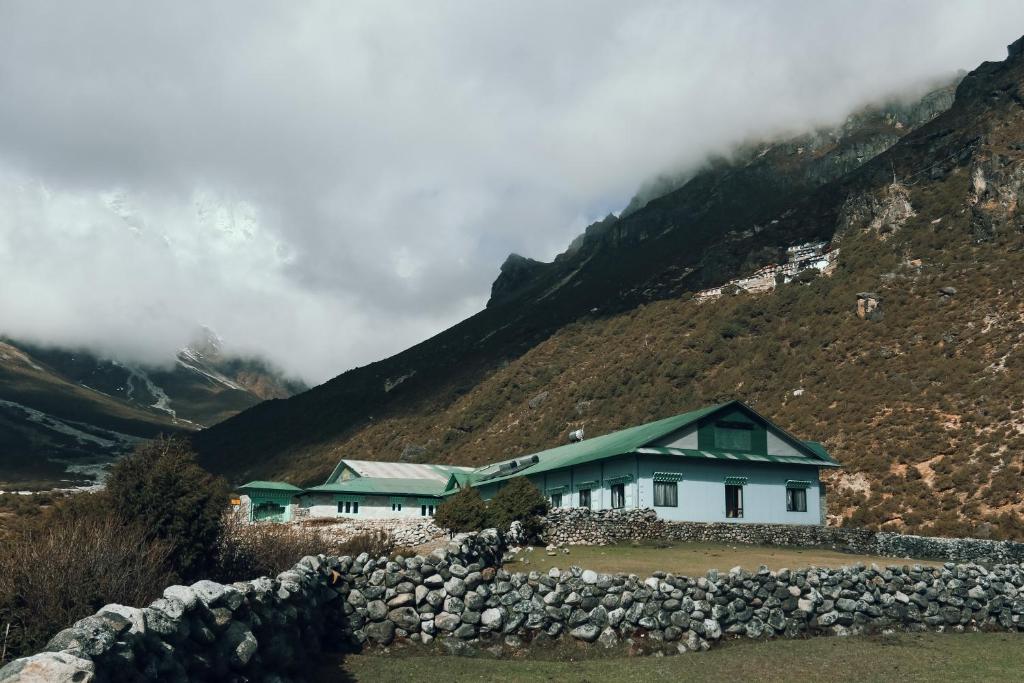 una casa frente a una montaña con nubes en Mountain Lodges of Nepal - Thame, en Thāmi