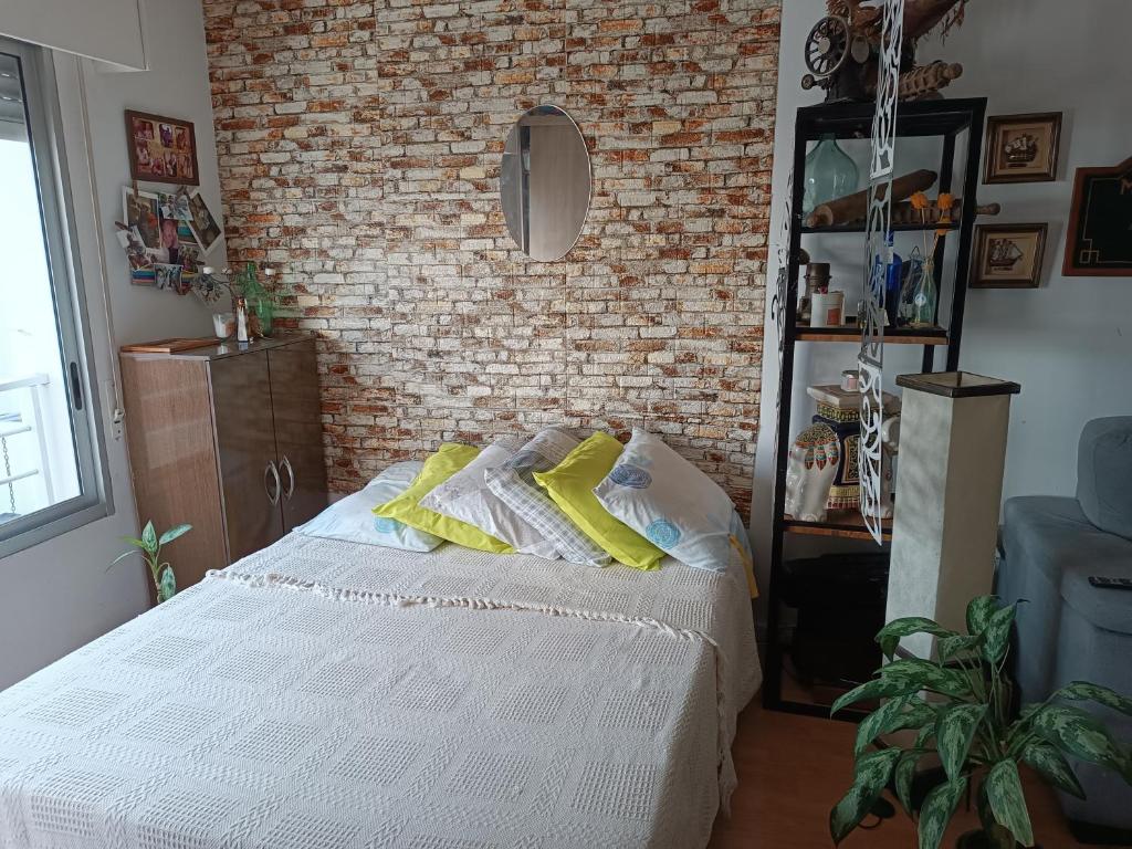 a bedroom with a bed and a brick wall at Monoambiente equipado en Pocitos cerca xoo y rambla in Montevideo