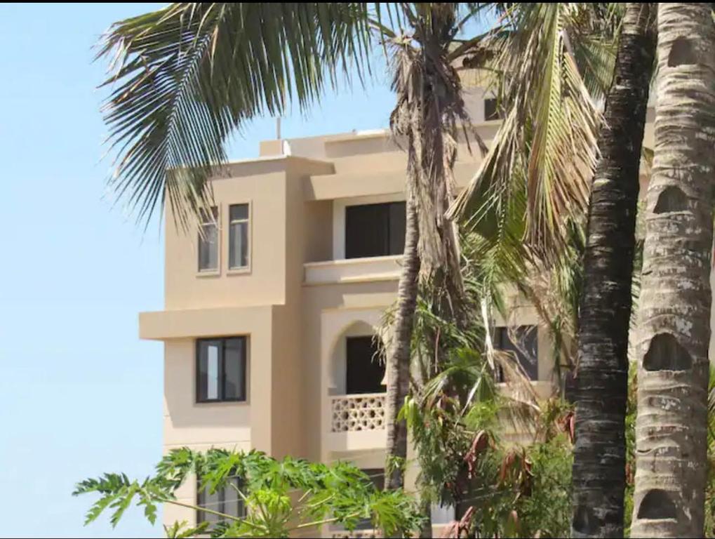 a house with palm trees in front of it at AC, 1 BR, 43 inch Smart TV, Hot shower- LightHouse in Mombasa