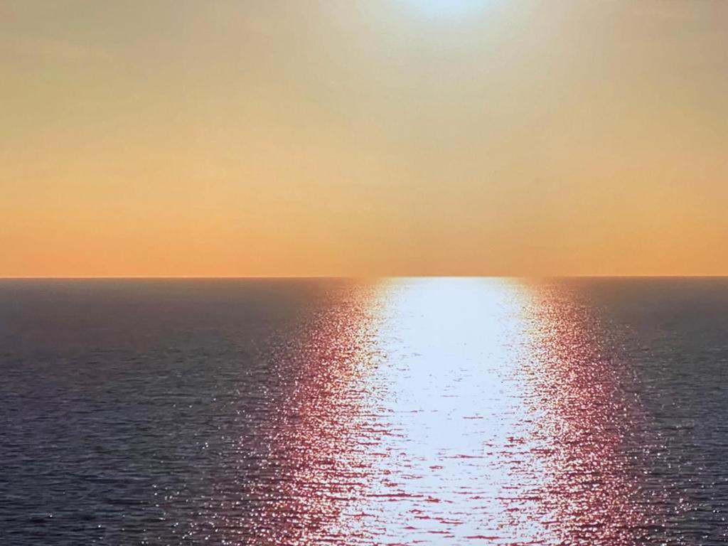 uma vista para o oceano com o sol refletindo sobre a água em Casa ONTINO em Sabaudia