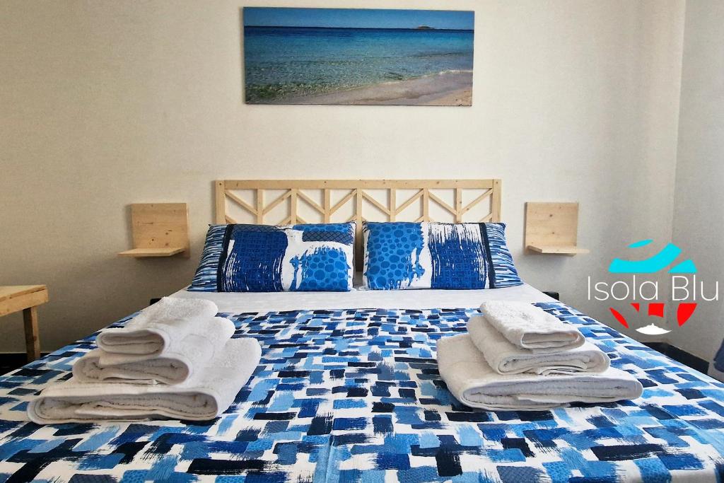 - une chambre avec un lit bleu et blanc et des serviettes dans l'établissement Isola Blu Casa a pochi passi dal mare, à Isola delle Femmine