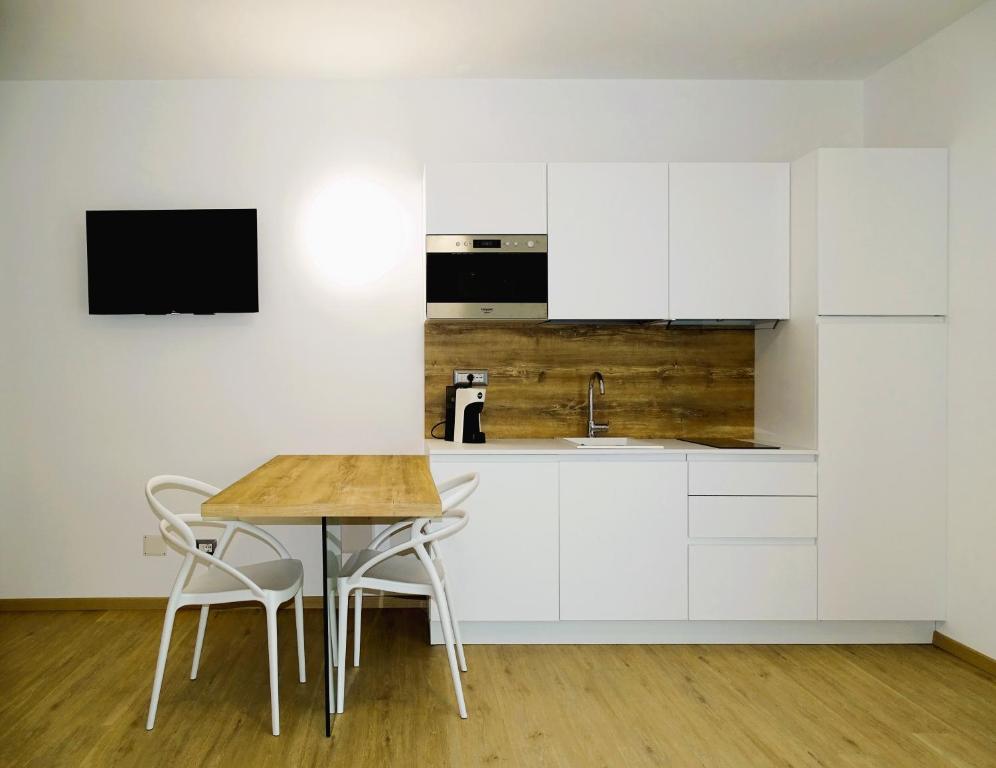 a kitchen with white cabinets and a wooden table at Residence Cala Bianca in Porto Torres