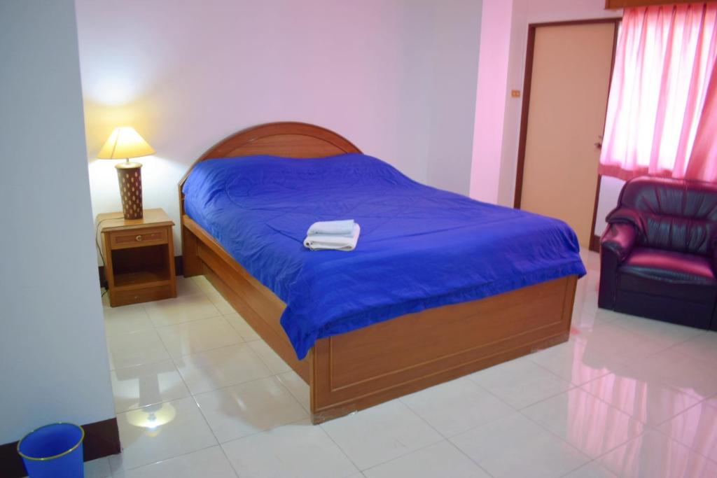 a bedroom with a bed with a blue blanket and a chair at My Hotel Bangkok Noi in Bangkok Noi