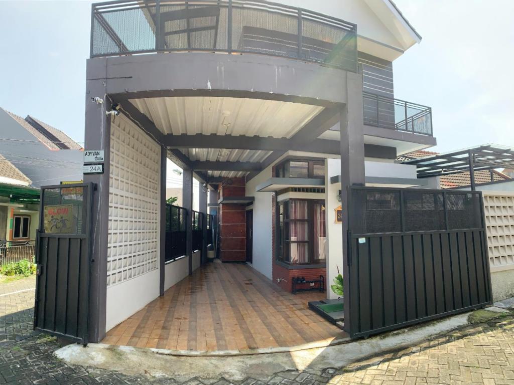 a house with a balcony and a wooden deck at Villa Dengan Kolam Renang di Malang in Malang