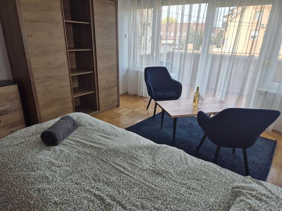 a bedroom with a bed and two chairs and a table at Charm Apartment in Kecskemét