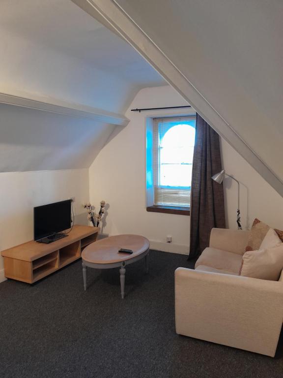 uma sala de estar com um sofá, uma mesa e uma televisão em Singleton Short Stay Loft R10 em Swansea