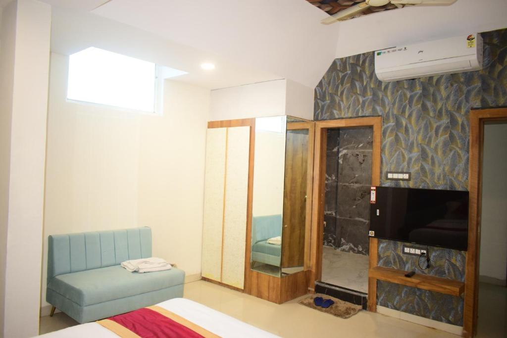 Habitación con TV, sofá y espejo. en Hotel Signor, en Indore