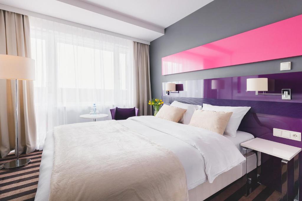 una camera con un letto bianco e una parete viola di Hola Hotel Katowice a Katowice