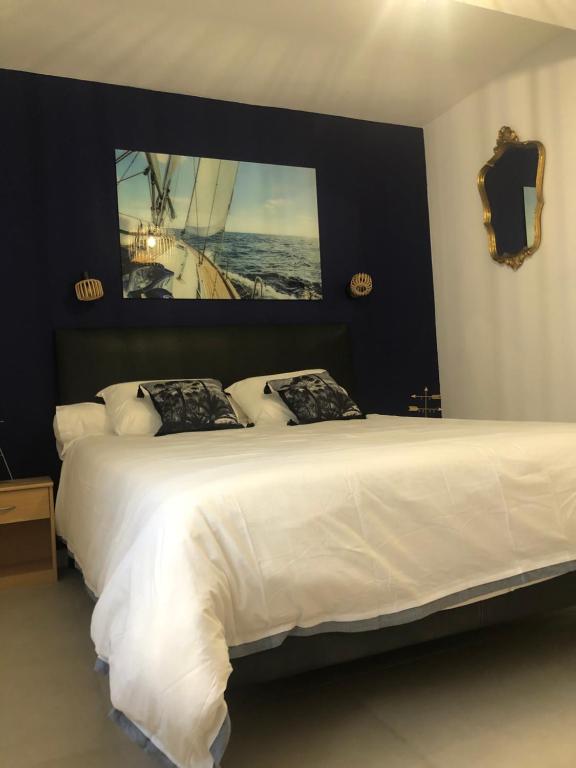 une chambre avec un grand lit blanc avec un tableau sur le mur dans l'établissement Agréable appartement Chez Mamé Jeanne au Grau du Roi, au Grau-du-Roi