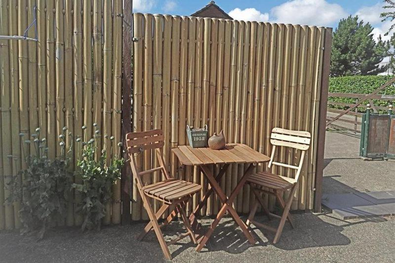 een houten tafel en twee stoelen naast een hek bij B&B De BonAparte Zomerhuis in Heemskerk