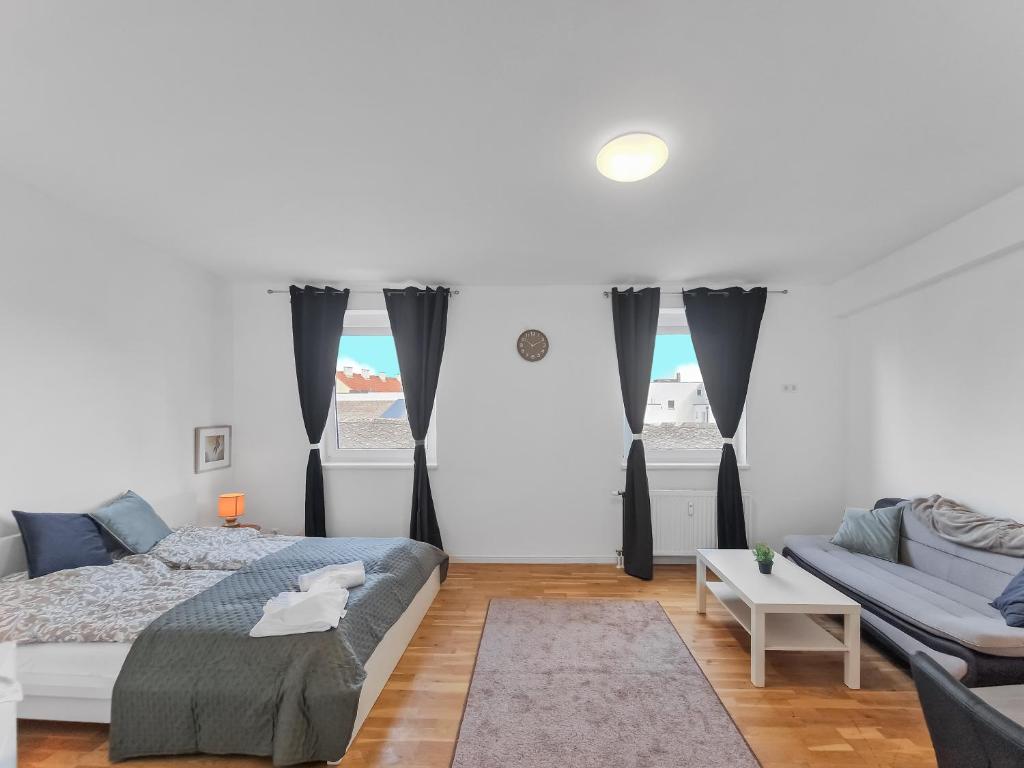 a white bedroom with a bed and a couch at Brodschildstraße apartment in Stockerau