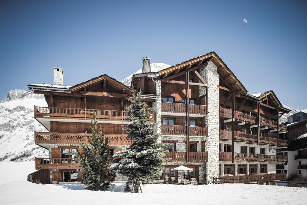 a building in the snow with a christmas tree in front at Hotel Altitude in Val-d'Isère