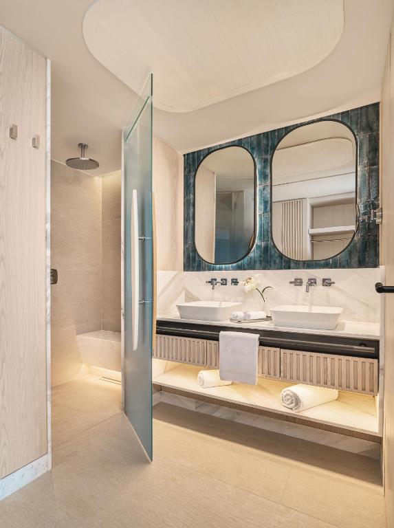 a bathroom with two sinks and two mirrors at Swissotel Resort And Spa Cesme in Çeşme