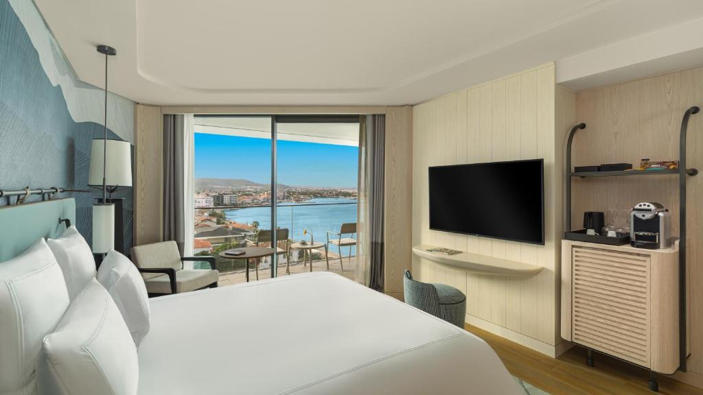 a hotel room with a bed and a television at Swissotel Resort And Spa Cesme in Çeşme