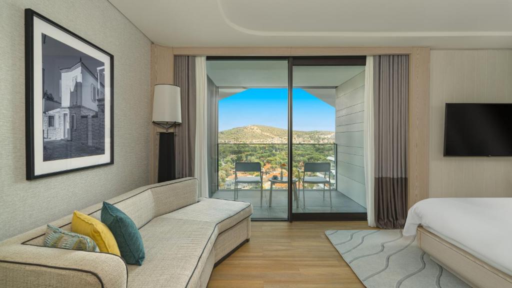 a living room with a couch and a bed and a television at Swissotel Resort And Spa Cesme in Çeşme