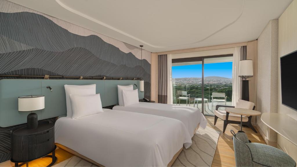 a hotel room with two beds and a balcony at Swissotel Resort And Spa Cesme in Çeşme