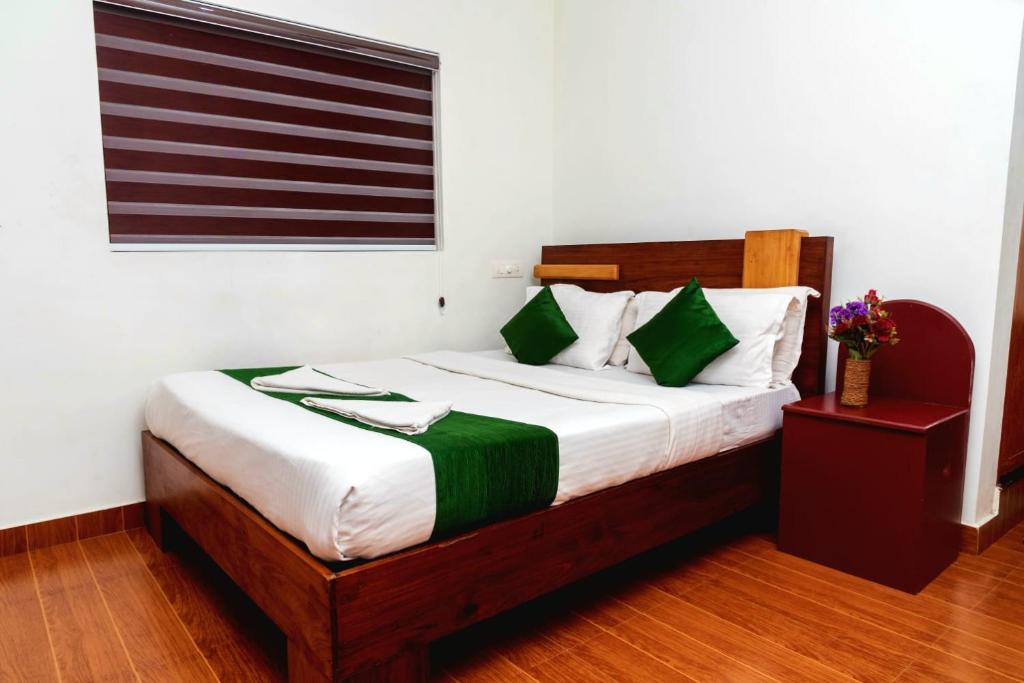 a bedroom with a bed with green and white pillows at pookode villa in Vythiri