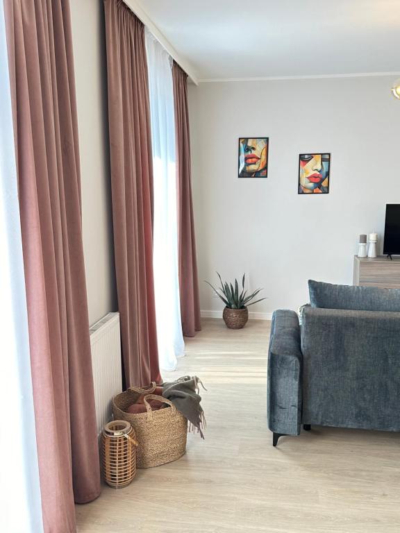 sala de estar con cortinas rosas y sofá azul en Apartament Łowca Snów, en Chełm