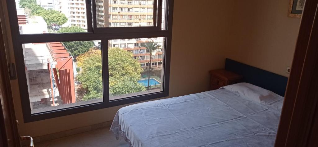 um quarto com uma cama e 2 janelas grandes em Apartamet Benidorm em Benidorm
