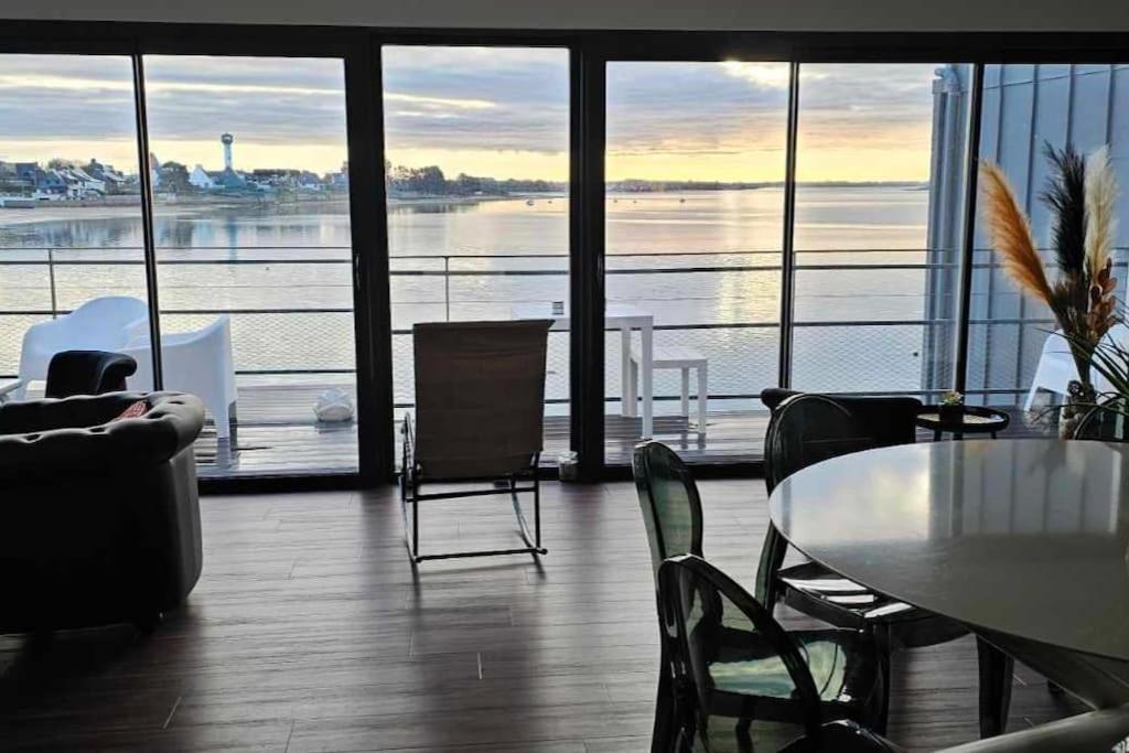 a room with a table and chairs and a view of the water at ARSAV Vue Mer et Plage in Port-Louis