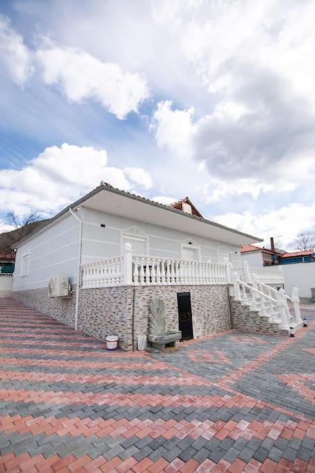 a white building with a balcony on a brick yard at Luxury House in Korçë