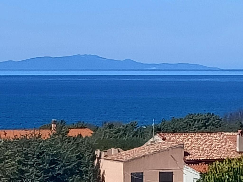 una casa di fronte all'oceano con montagne sullo sfondo di Villa Marina a Sorso