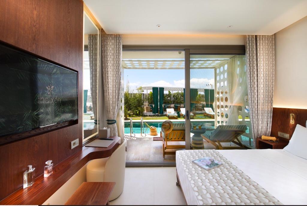 a bedroom with a bed and a television and a balcony at Voger Alaçatı Prive in Cesme