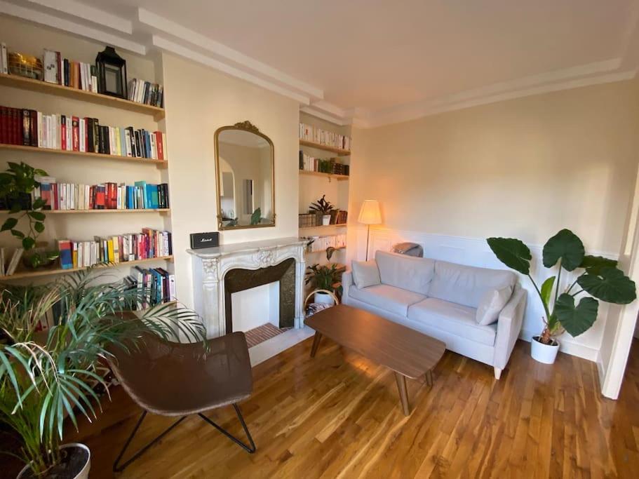 Appartement de charme Quartier des Batignolles في كليشي: غرفة معيشة مع أريكة بيضاء ومدفأة