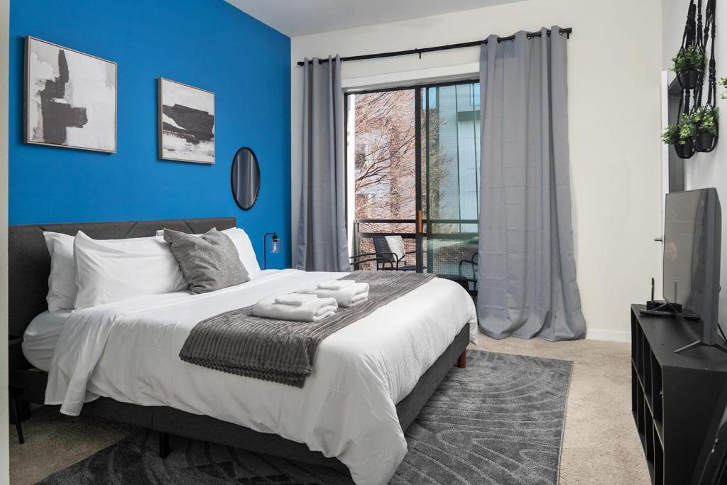 a bedroom with blue walls and a bed and a window at Spacious 2BD with Private Balcony and Free Parking in Charlotte