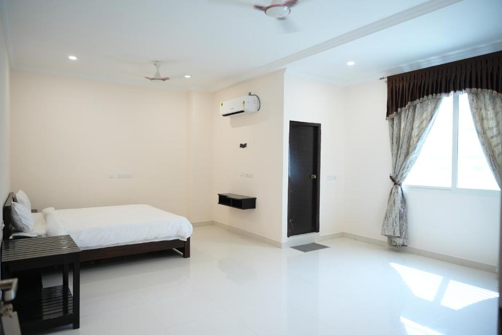 a white bedroom with a bed and a window at SABA SERVICE APARTMERNT in Hyderabad
